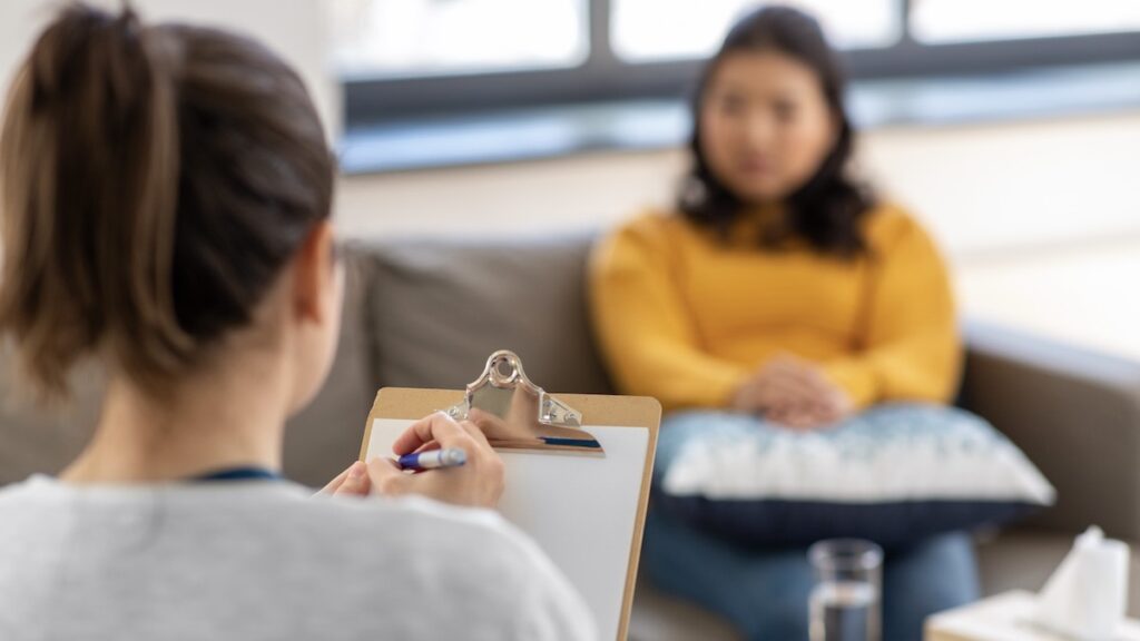 Stock photo of female therapist listening to a client in an office setting.
