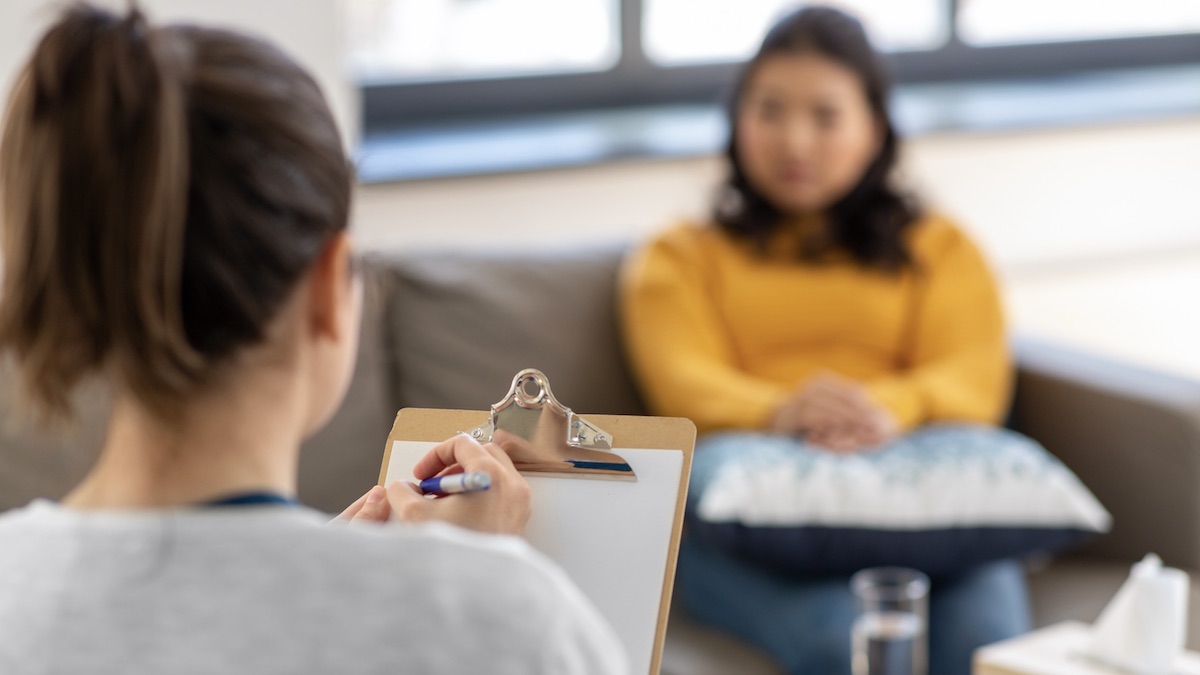Stock photo of female therapist listening to a client in an office setting.