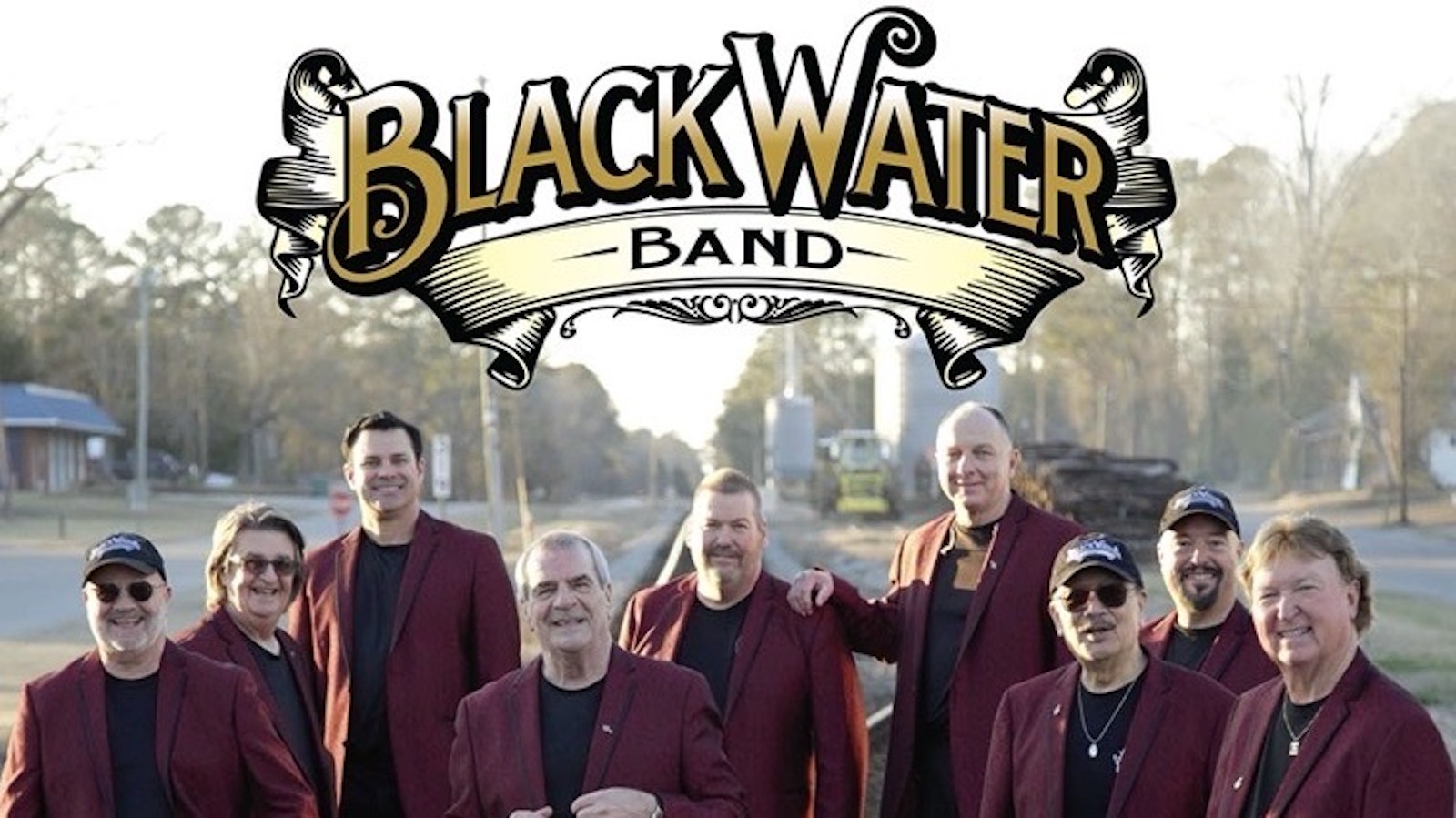Band members for the BlackWater Band pose outside in rural setting.