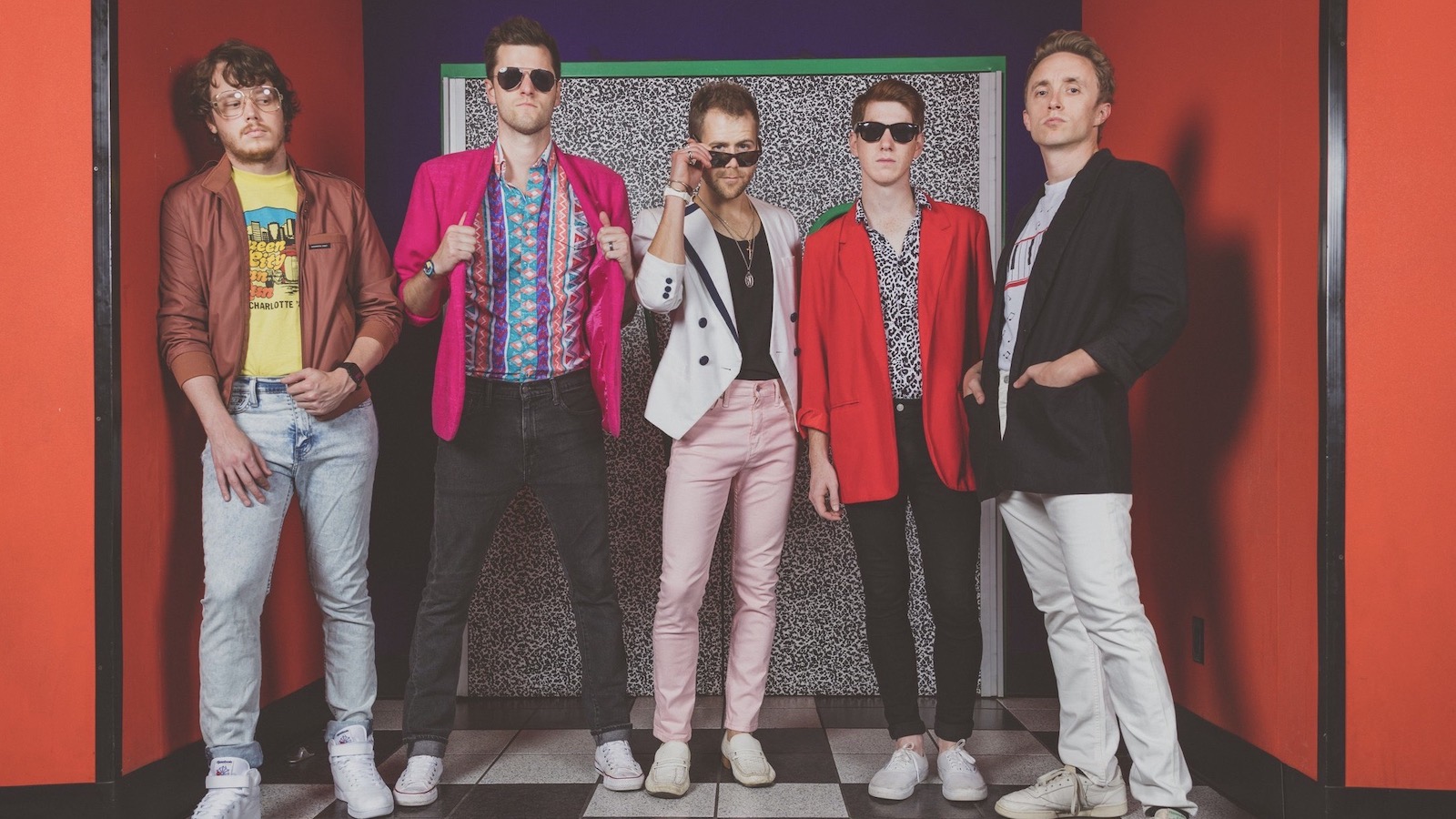 Members from the band Cassette Rewind pose in colorful 1980's attire.