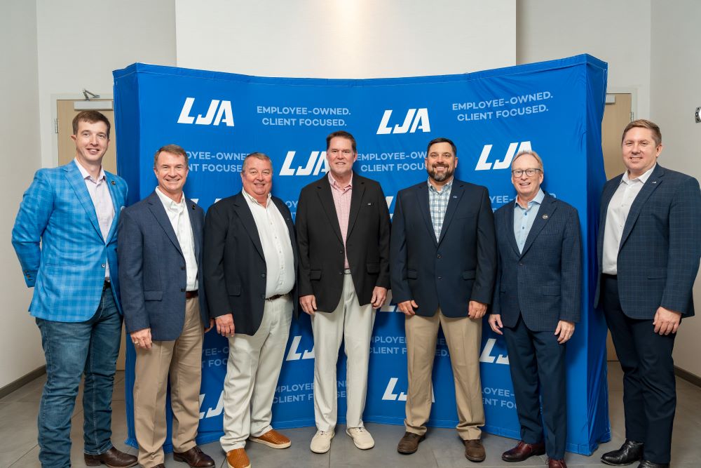 7 men standing in front of blue LJA banner