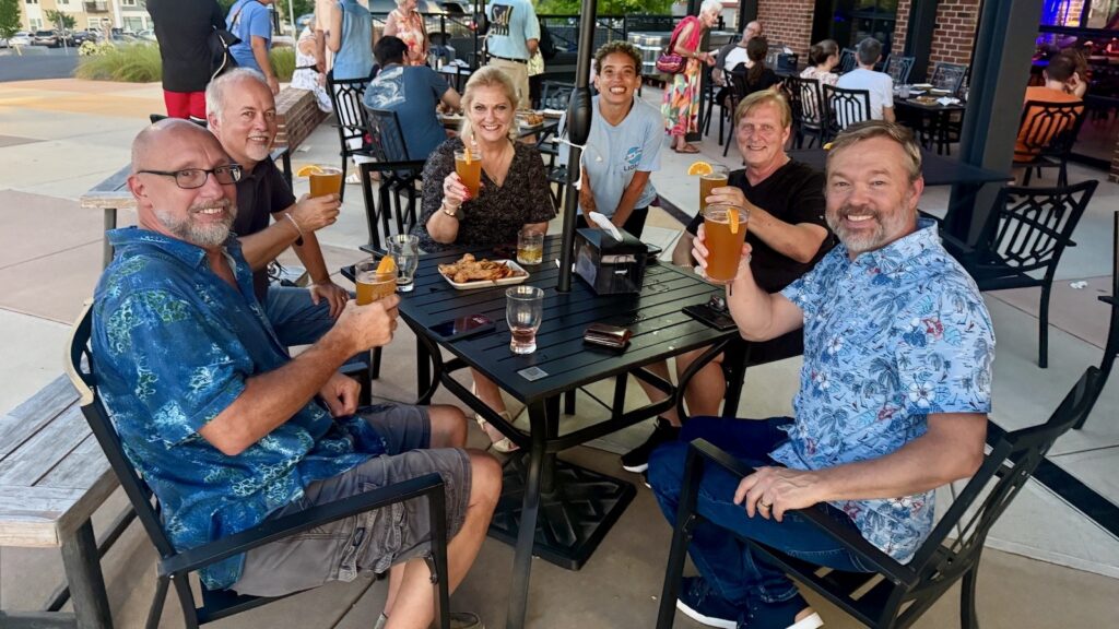 Men and women sitting outside at a restaurant toasting with drinks