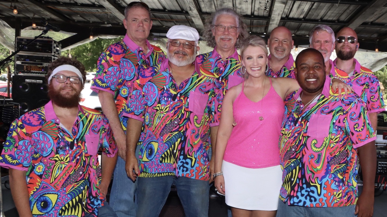 Band members from The Extraordinaires pose in biright colored shirts on stage.