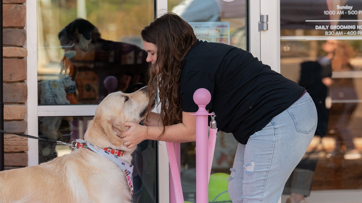Woman in front of Woof Gang Pittsboro petting golden retriever
