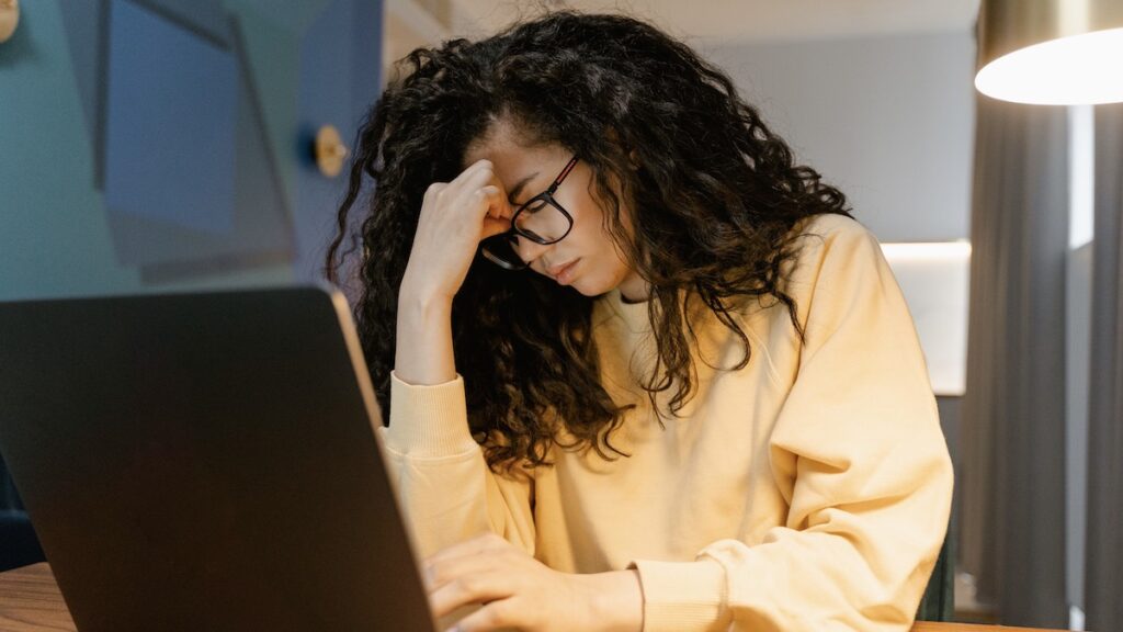 Women sitting at desk with computer and head in her hands